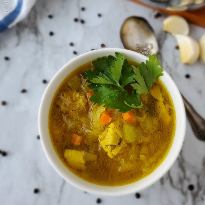 close up of the keto chicken soup in a bowl with a bay leaf on top