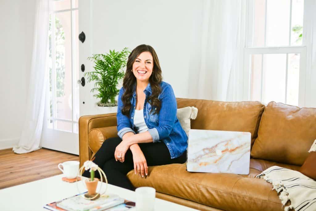 Amy Porterfield sitting on the couch with laptop