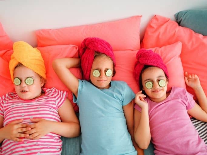 three little girls with hair in towels and eyes covered with cucumbers