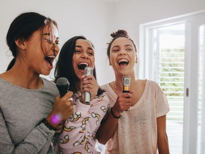 three girls singing into microphones