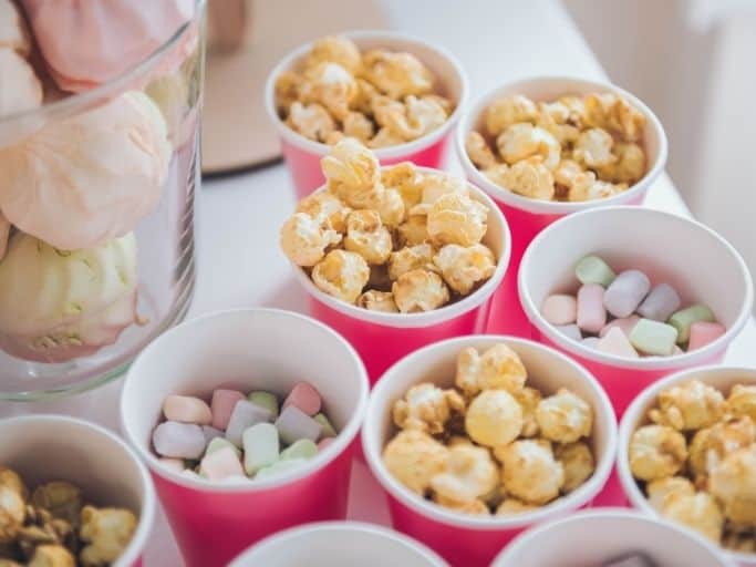 popcorn bar with different options of popcorn and candy in each pink cup