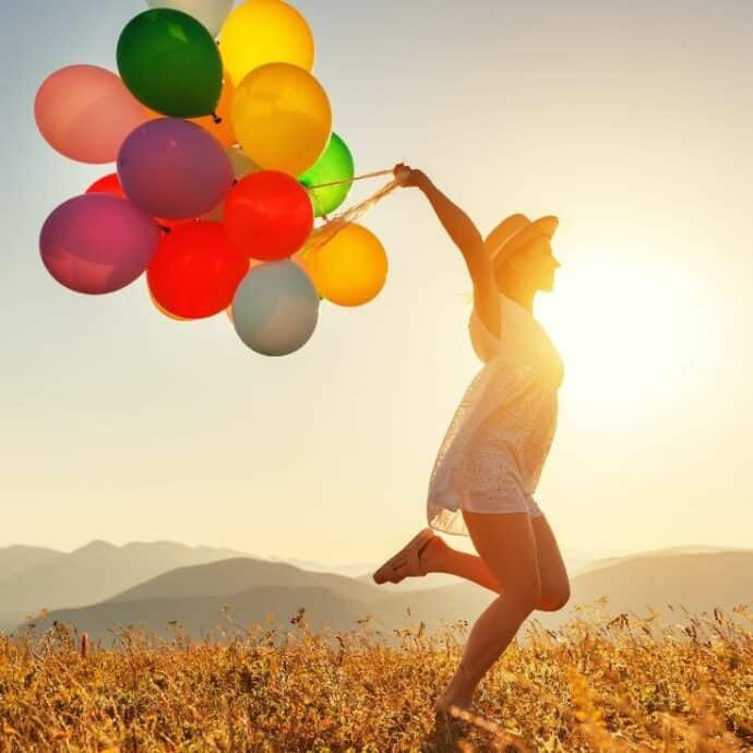 woman with a bunch of balloons running outside