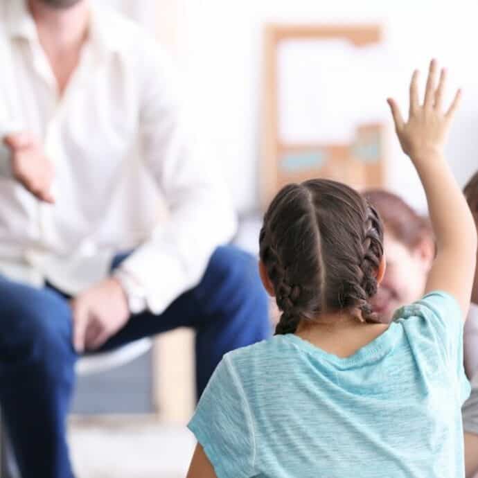 girl raising her hand in class