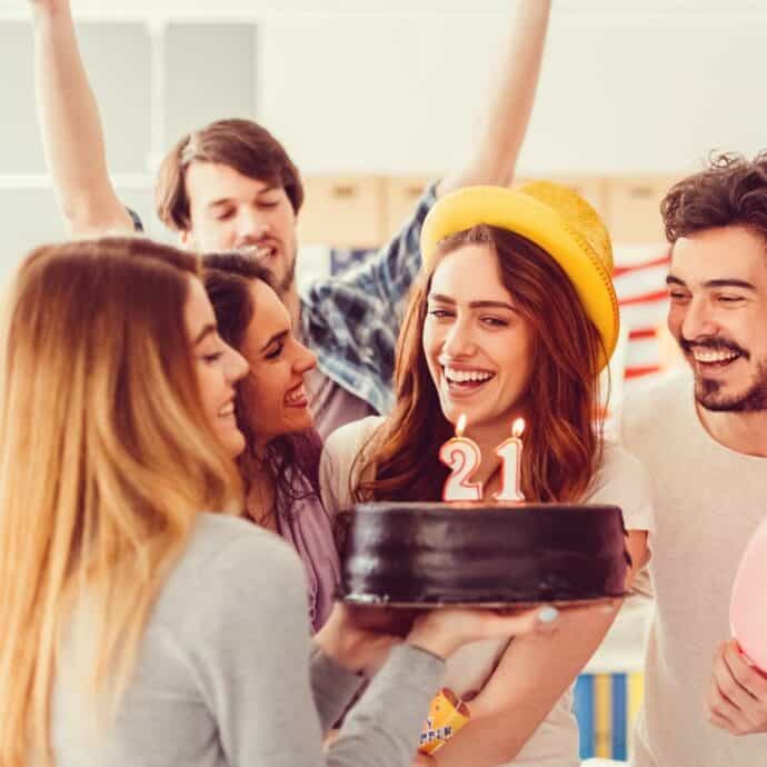 friends celebrating a 21st birthday with a cake and a small party