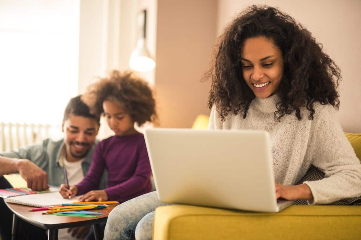 mom working from home on a laptop while dad and kid color