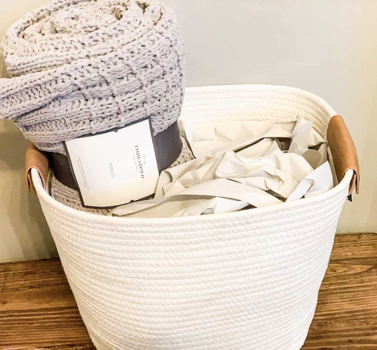 basket with tissue paper stuffed in it and the blanket sticking out