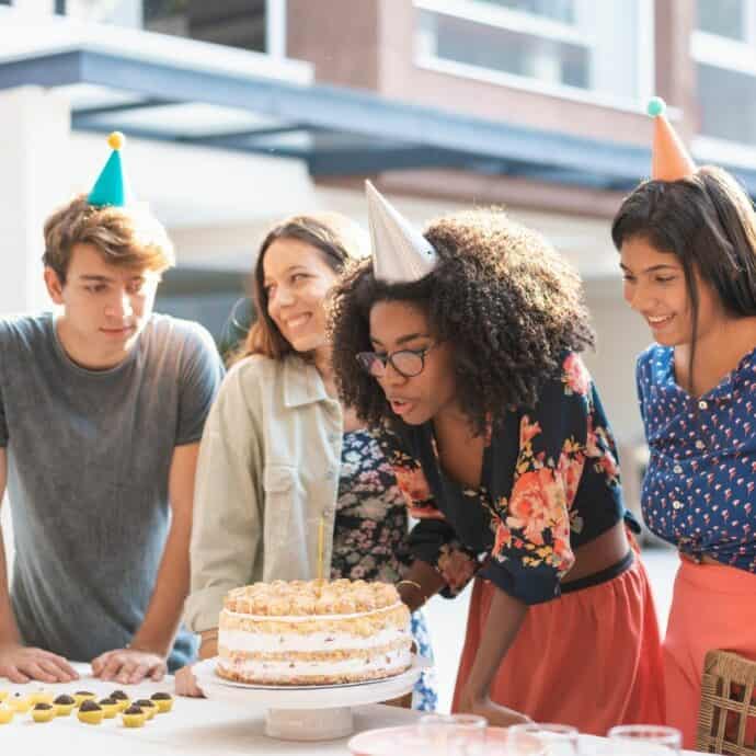 girl blowing out birthday candles with 3 friends