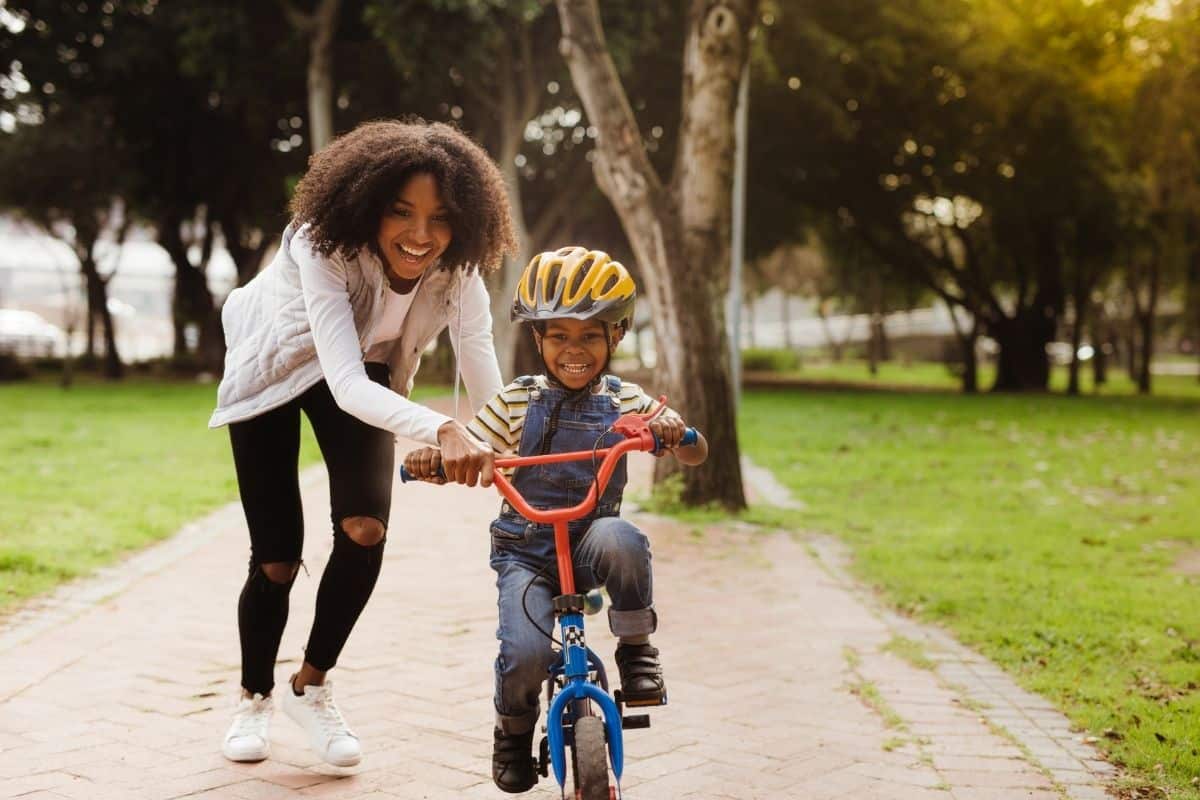 young mom helping her son ride a bike