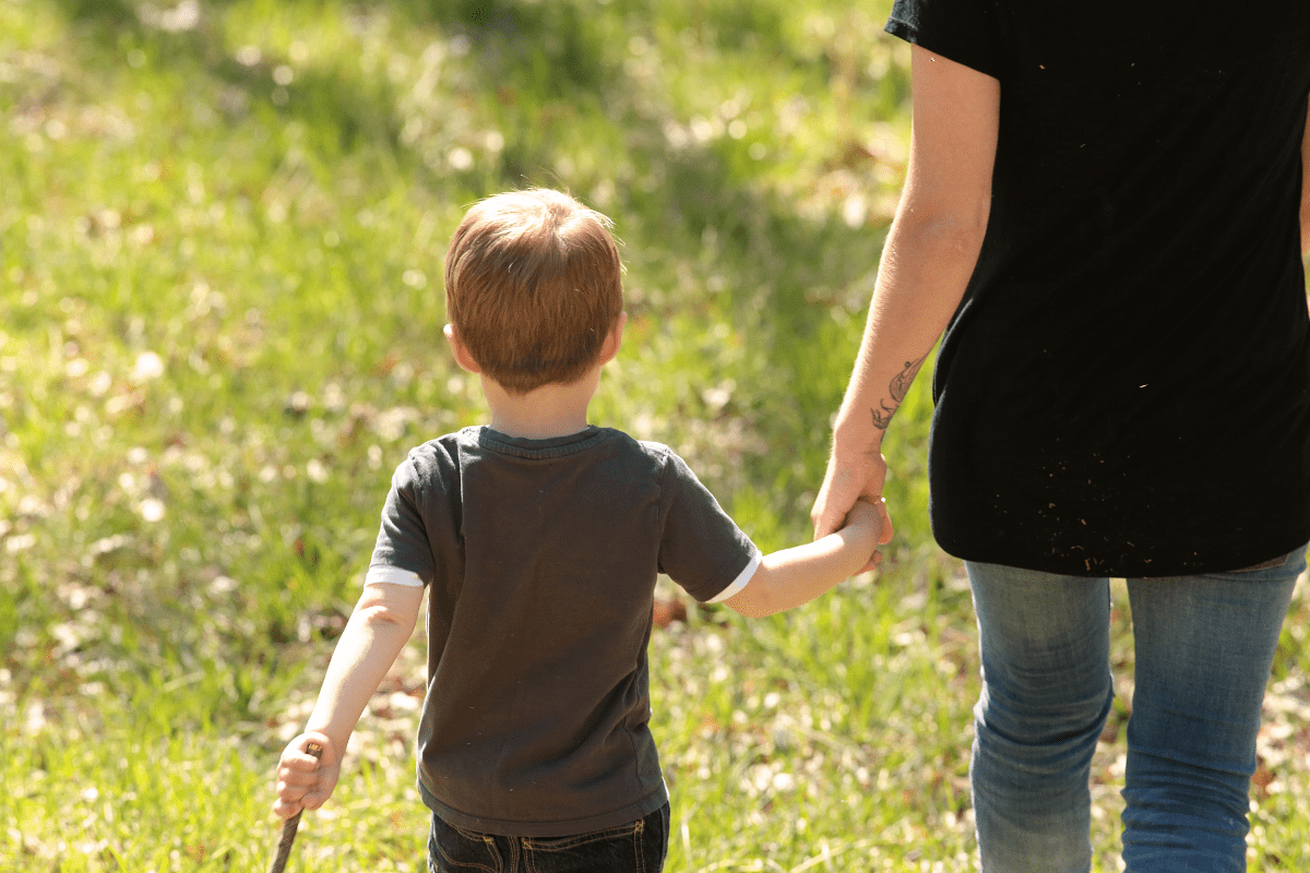 little boy holding his mom's hand outside