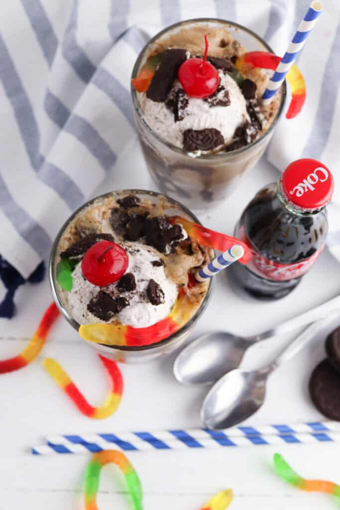 2 cookies and cream ice cream floats with candy on top - next to a bottle of coca cola