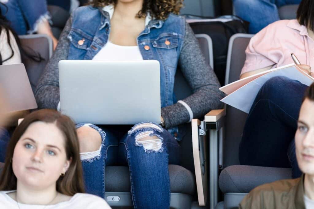 a close up of a girl taking notes on her laptop in class