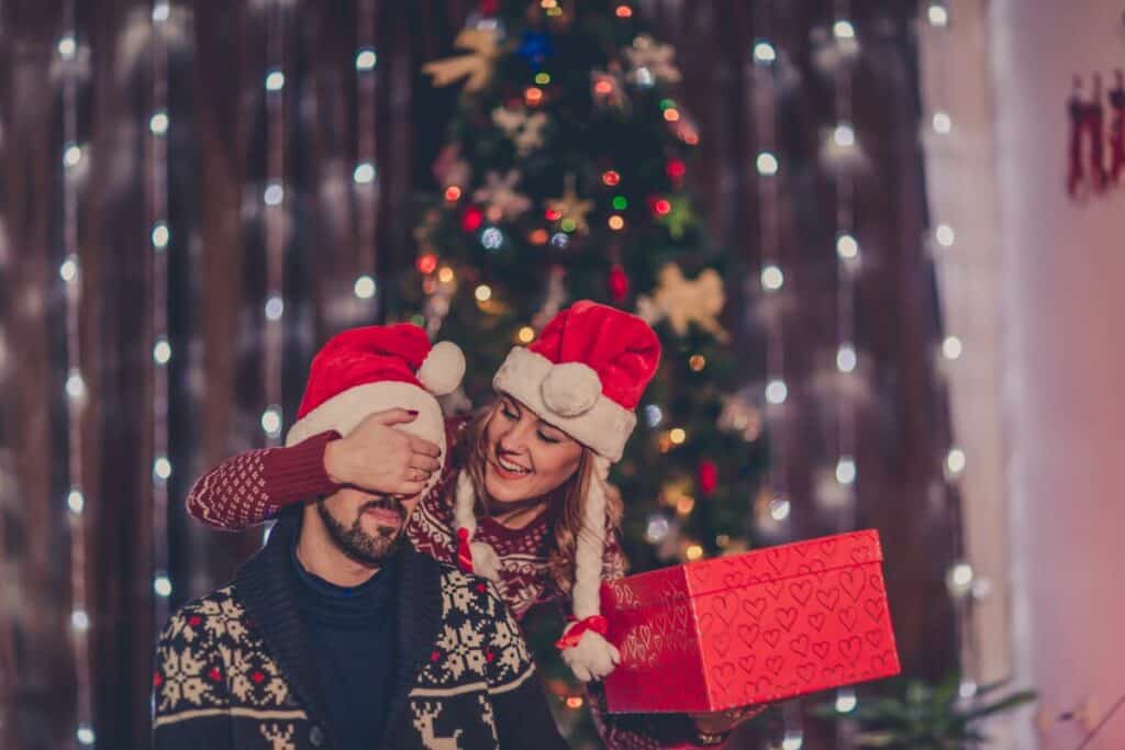 couple opening up a present with santa hats on