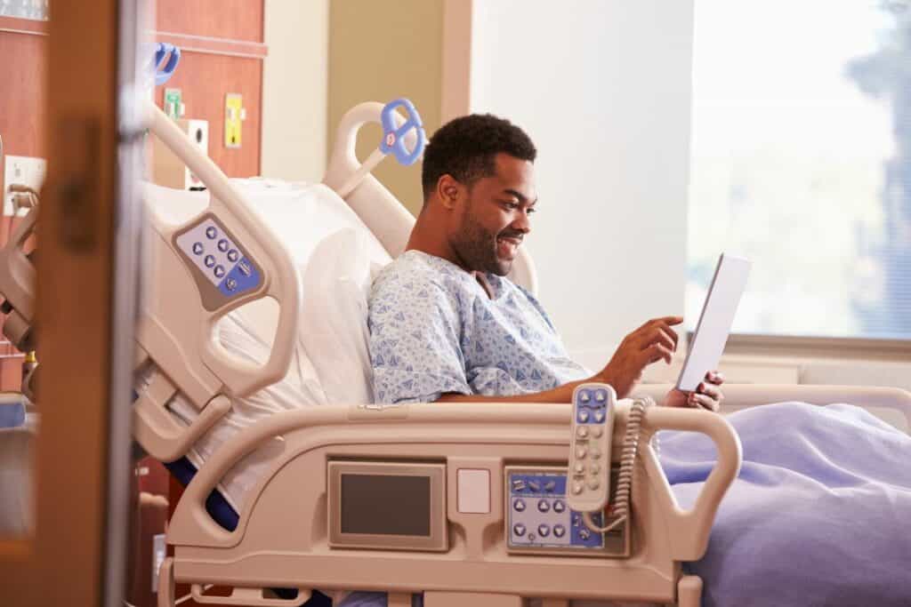 smiling black man in bed with an ipad