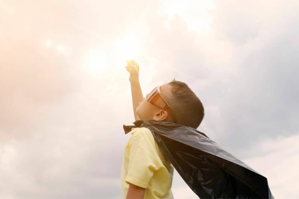 boy pretending to be superman with cape on