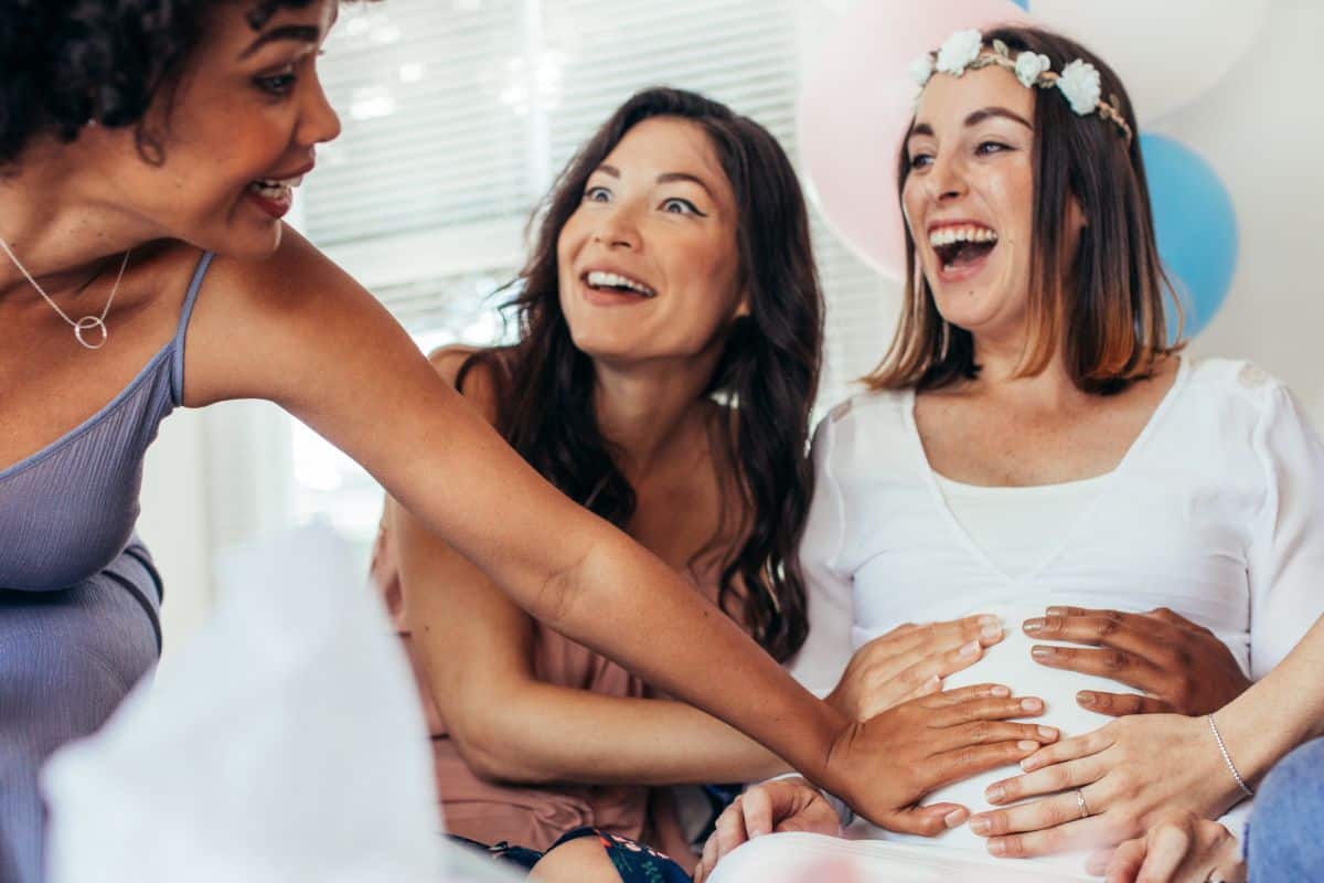 friends at a baby shower with hands on the mother to be's belly