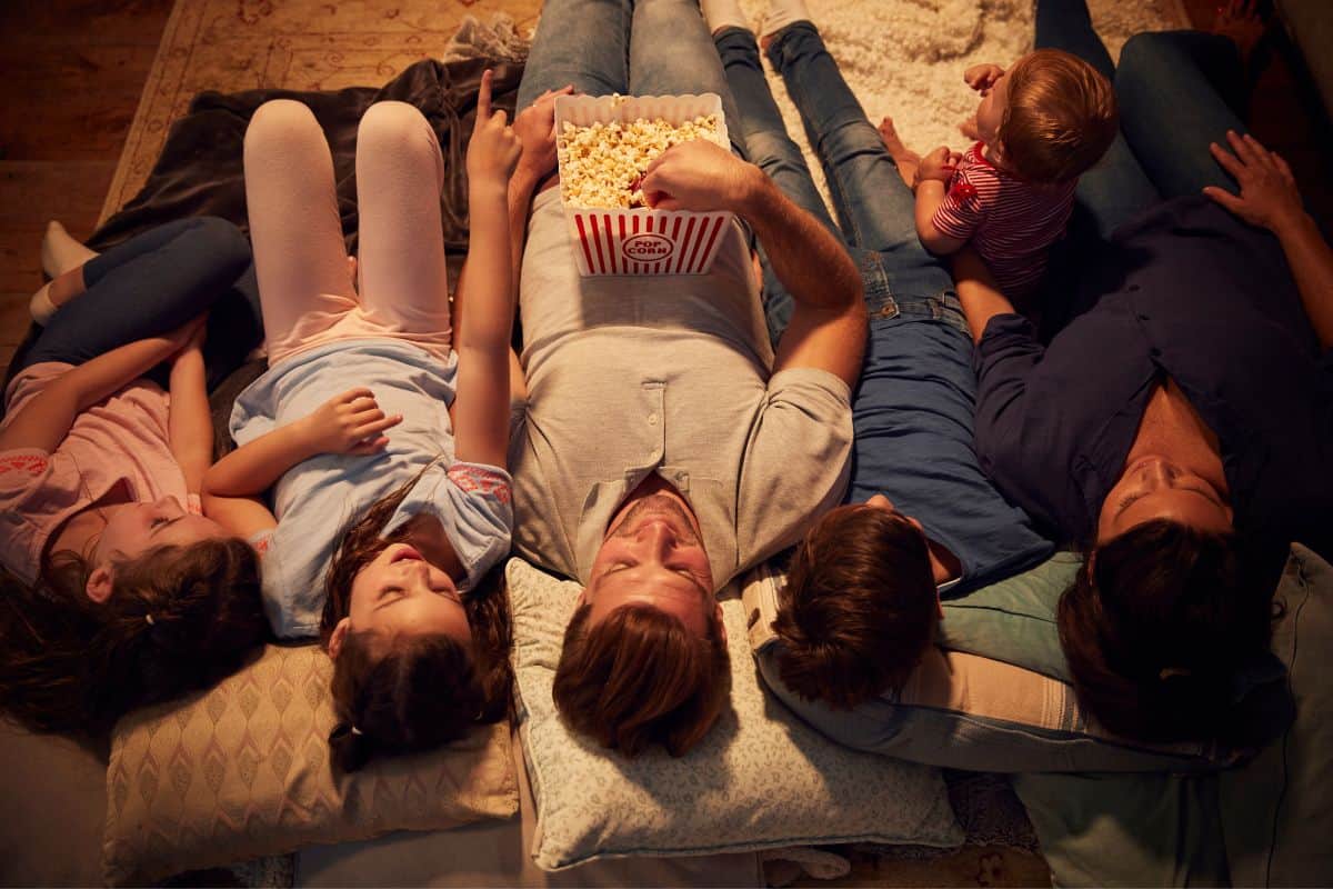 family watching as movie in the dim room on pillows