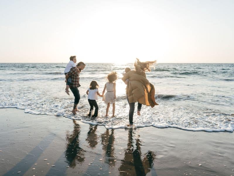 family on the beach standing at the edge of the water