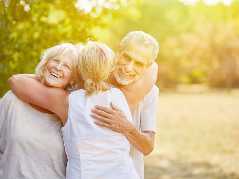 an adult daughter hugging her mom and father