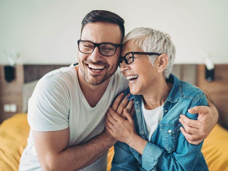 adult son hugging and laughing with his mom at home