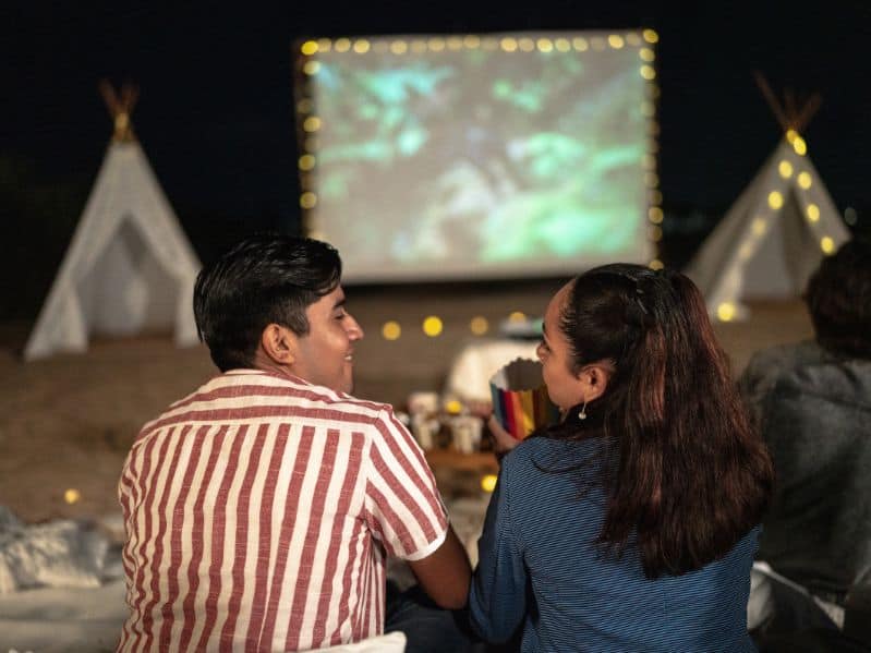 couple outside for an romantic picnic at night watching a movie