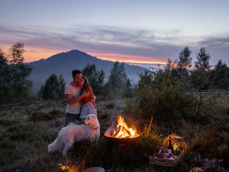 couple with their dog enjoying a bonfire