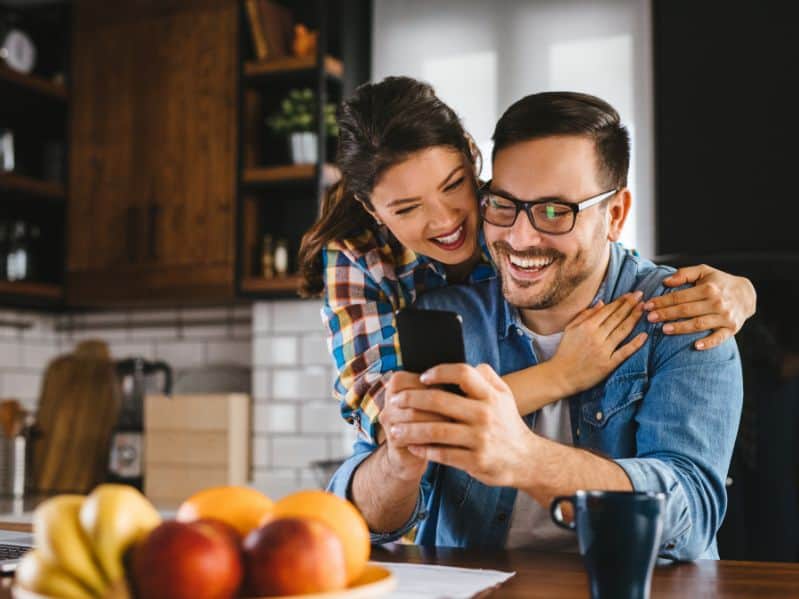 couple looking at a new phone in their kitchen