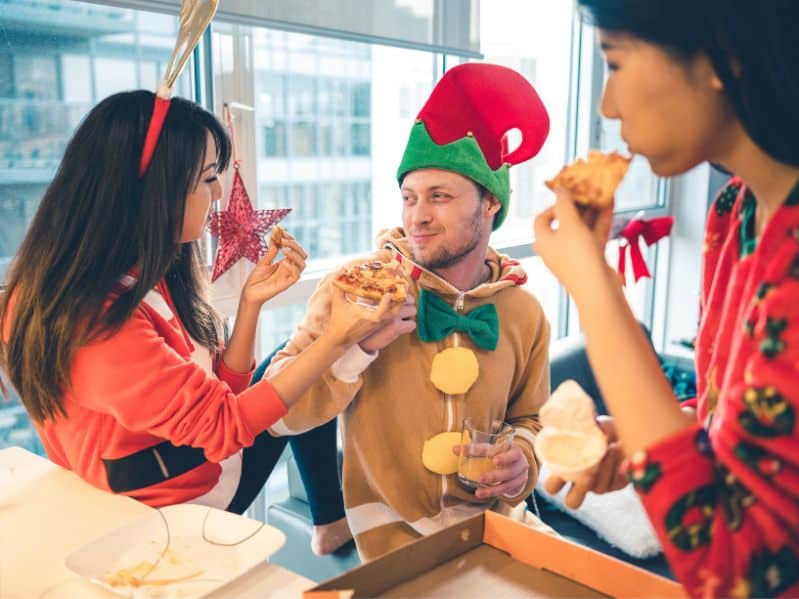 friends enjoying pizza in silly Christmas pajamas