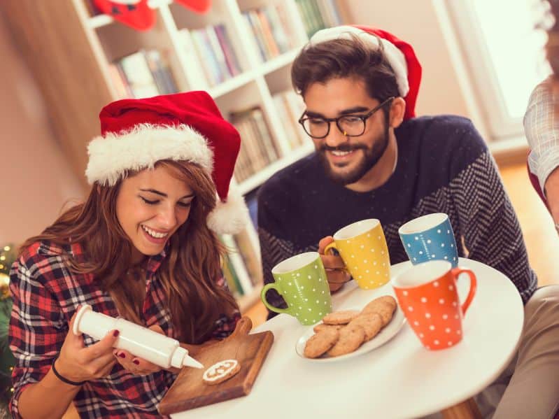 couple decorating cookies while wearing santa hats