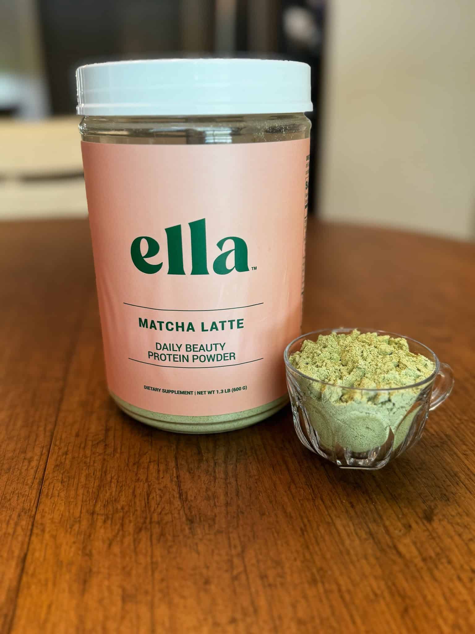 Naked Nutrition's Ella Matcha Latte Collagen Peptides in a glass bowl with the canister beside it