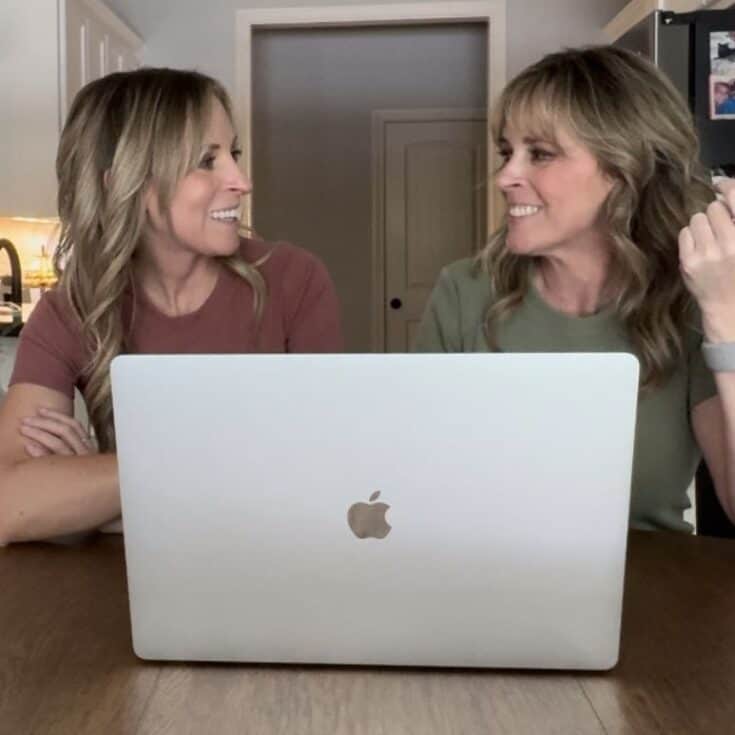 Kim and Kalee at the table looking at each other and their laptop