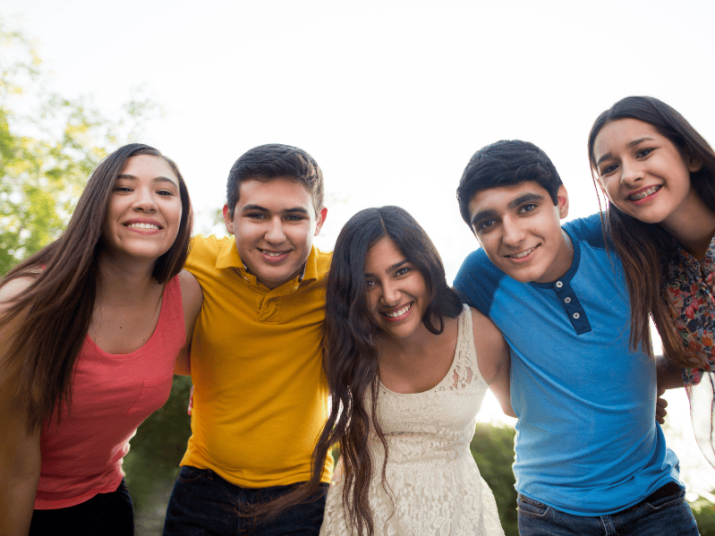 5 teenagers smiling together for the camera